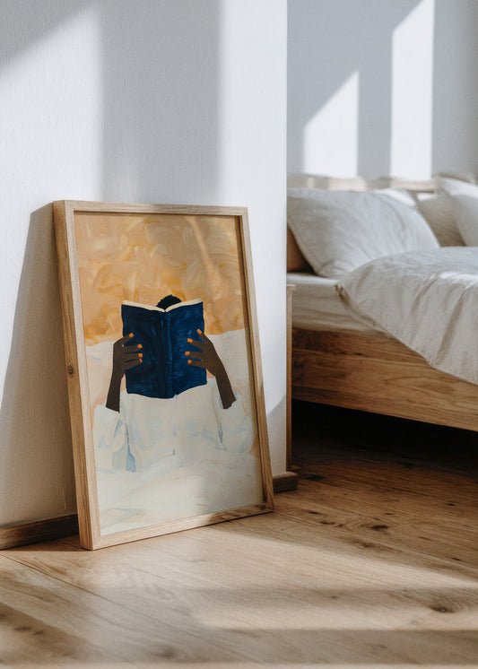 Must Read poster leaning against a white wall in a sunlit bedroom with natural wood furniture