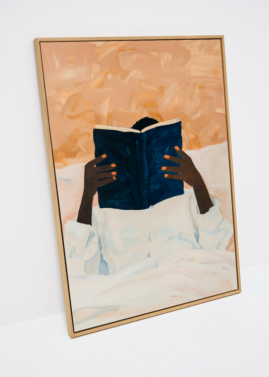 Canvas print of a person reading a dark blue book in bed, with soft beige background and expressive orange fingernails – Must Read from HelloPoster.
