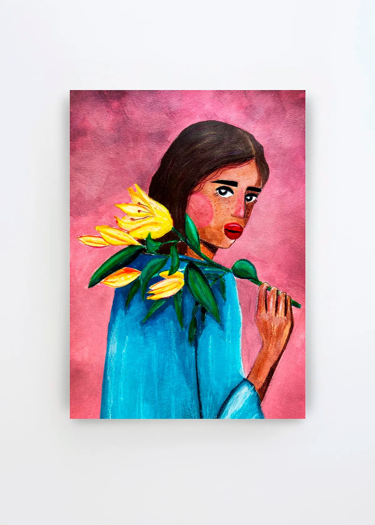 Woman With Lily plakat af Raissa Oltmanns med en kvinde i blå bluse, mørkt hår og gule liljer på en varm pink baggrund.
