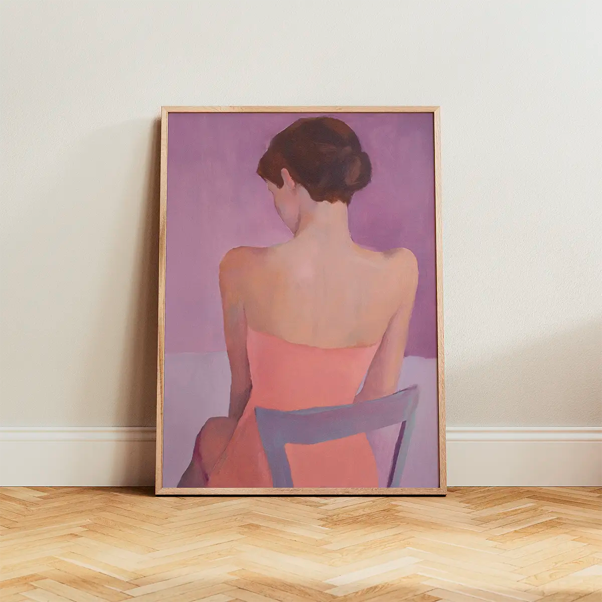 Poster of a woman seen from behind in soft pink and purple tones, framed in oak and placed on a parquet floor against a light wall, minimal Scandinavian home decor.