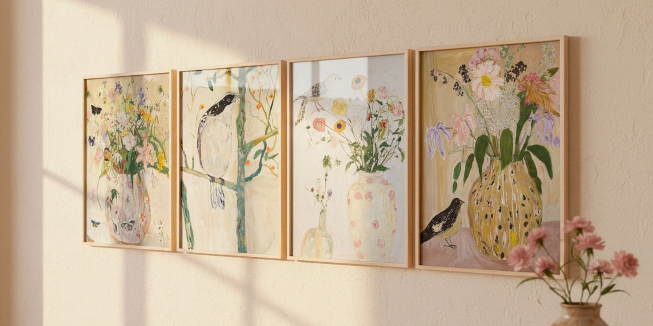 Bird 1, Bird 2, Bird 3 and Wild Garden posters displayed in oak frames on a sunlit beige wall, styled with delicate floral details in a Scandinavian interior.