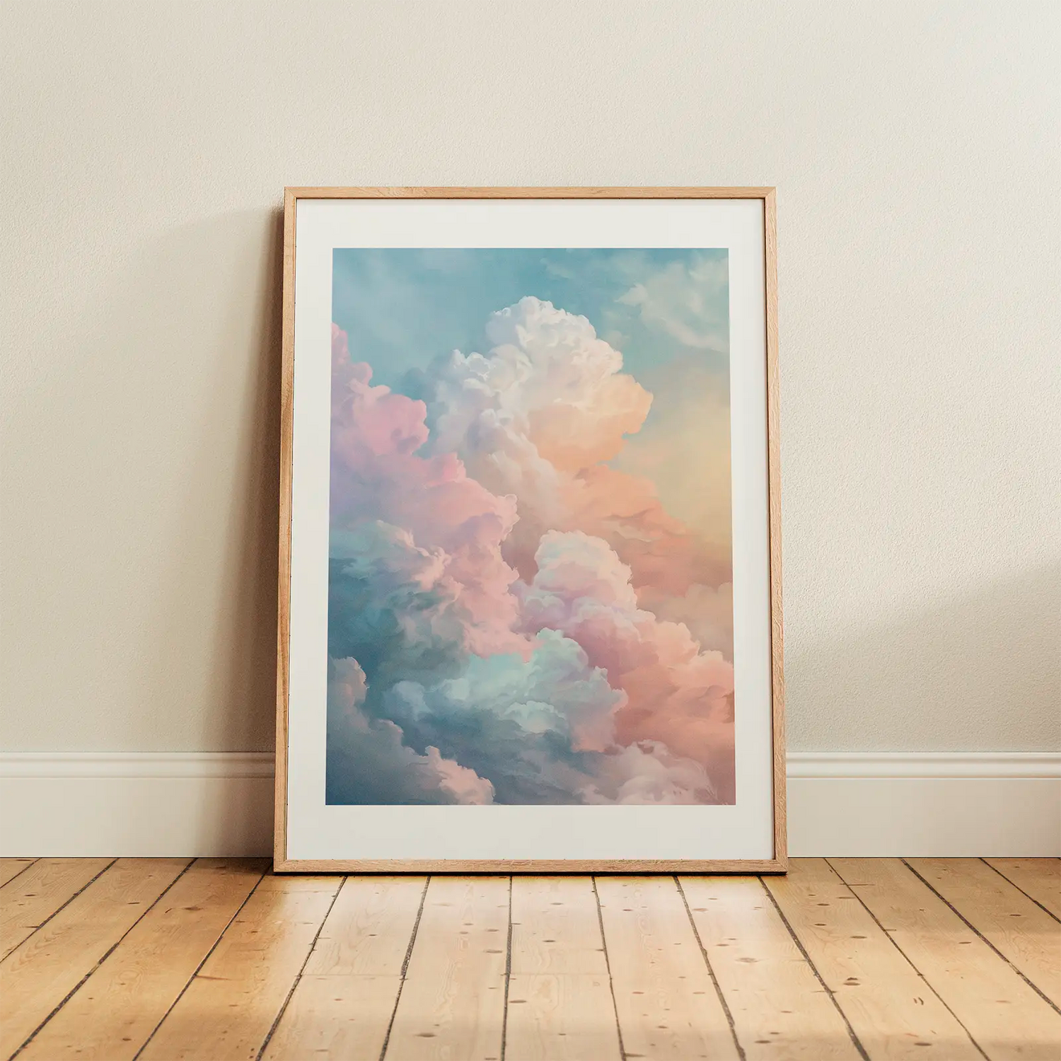 Pastel cloud poster in a light oak frame leaning against a white wall on wooden flooring in a bright Scandinavian room.
