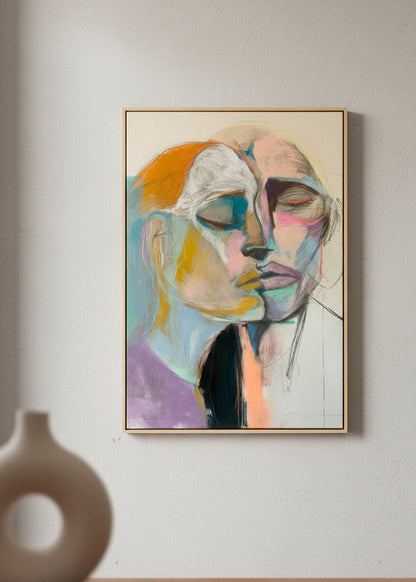 “Lovers” canvas print featuring two abstract faces merging in soft pastel tones, displayed in a minimalist room with neutral decor.
