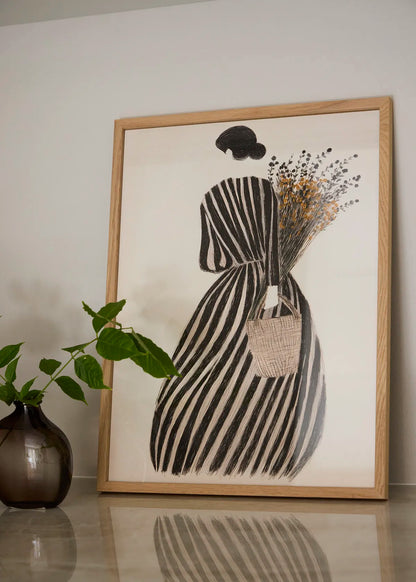 MariGold flower poster in an oak frame styled in a neutral interior with a dark vase, green leaves and warm natural tones.