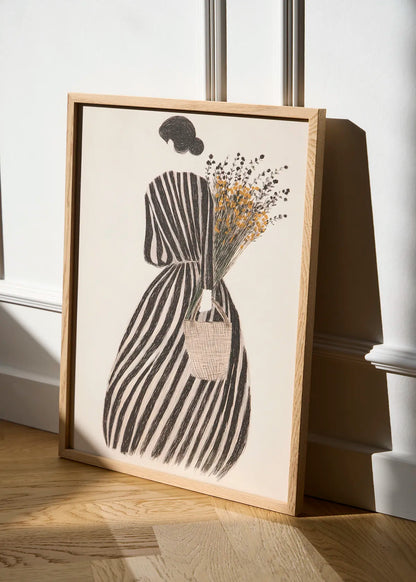 MariGold woman poster in an oak frame leaning against a white wall in natural sunlight, featuring black stripes and golden wildflowers.
