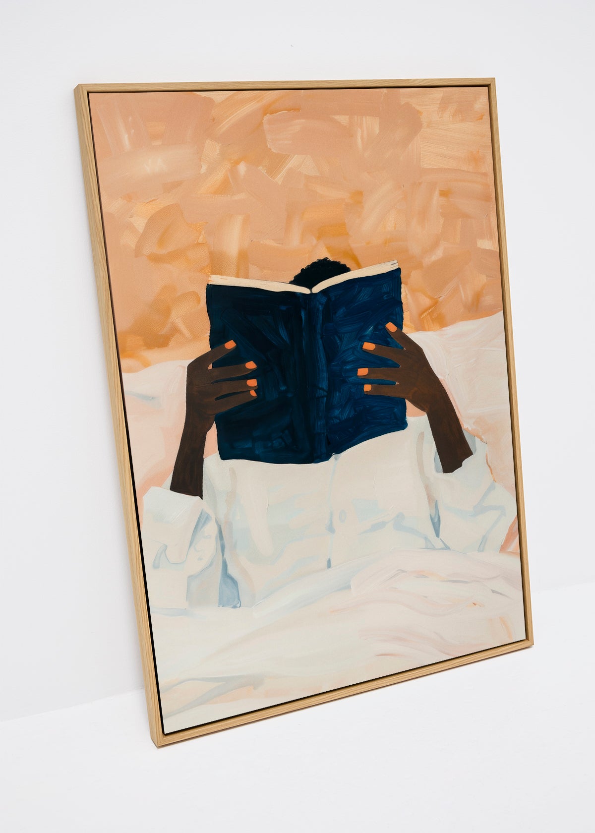 Canvas print of a person reading a dark blue book in bed, with soft beige background and expressive orange fingernails – Must Read from HelloPoster.