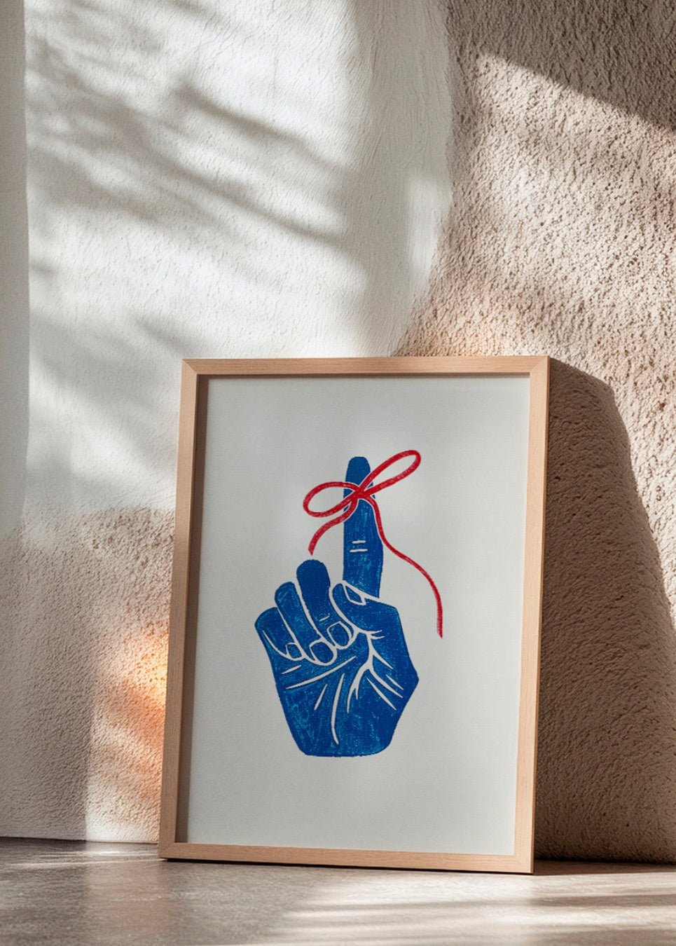 Graphic 'Remember' poster with a red string tied around a blue hand, leaning against a sunlit wall.