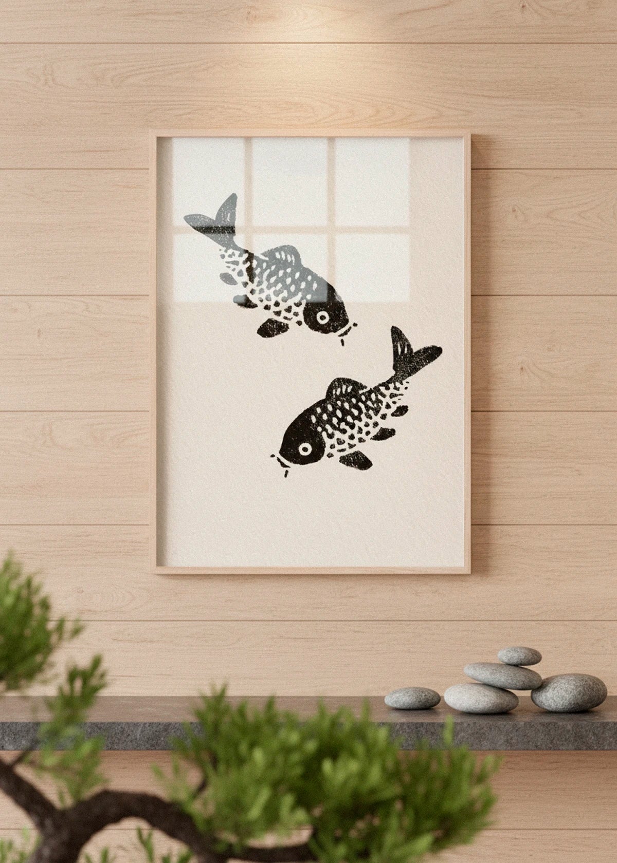 The Sakana poster with two black koi fish, hanging on a wooden wall in a serene Japanese-inspired setting.