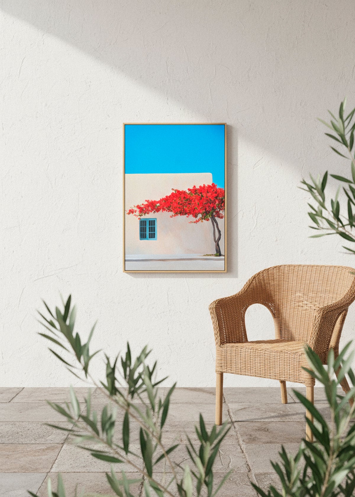 Framed “Siesta” canvas print leaning against a white wall in natural sunlight, surrounded by red flowers and soft shadows.