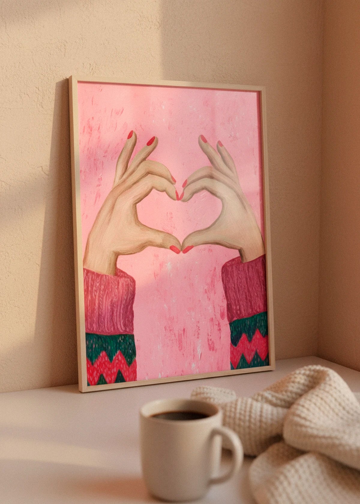 Sweater Love poster in a wooden frame leaning against a warm beige wall, styled with soft morning sunlight, cozy knit blanket and a cup of coffee.