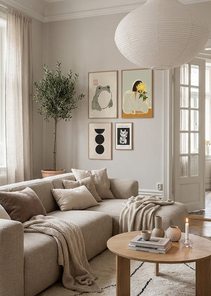 Bright Scandinavian living room styled with Hello Poster gallery wall featuring The Crysanthemum, Grumpy Frog, Boulder and Manekineko posters in oak frames above a beige sofa with soft neutral decor and natural light.