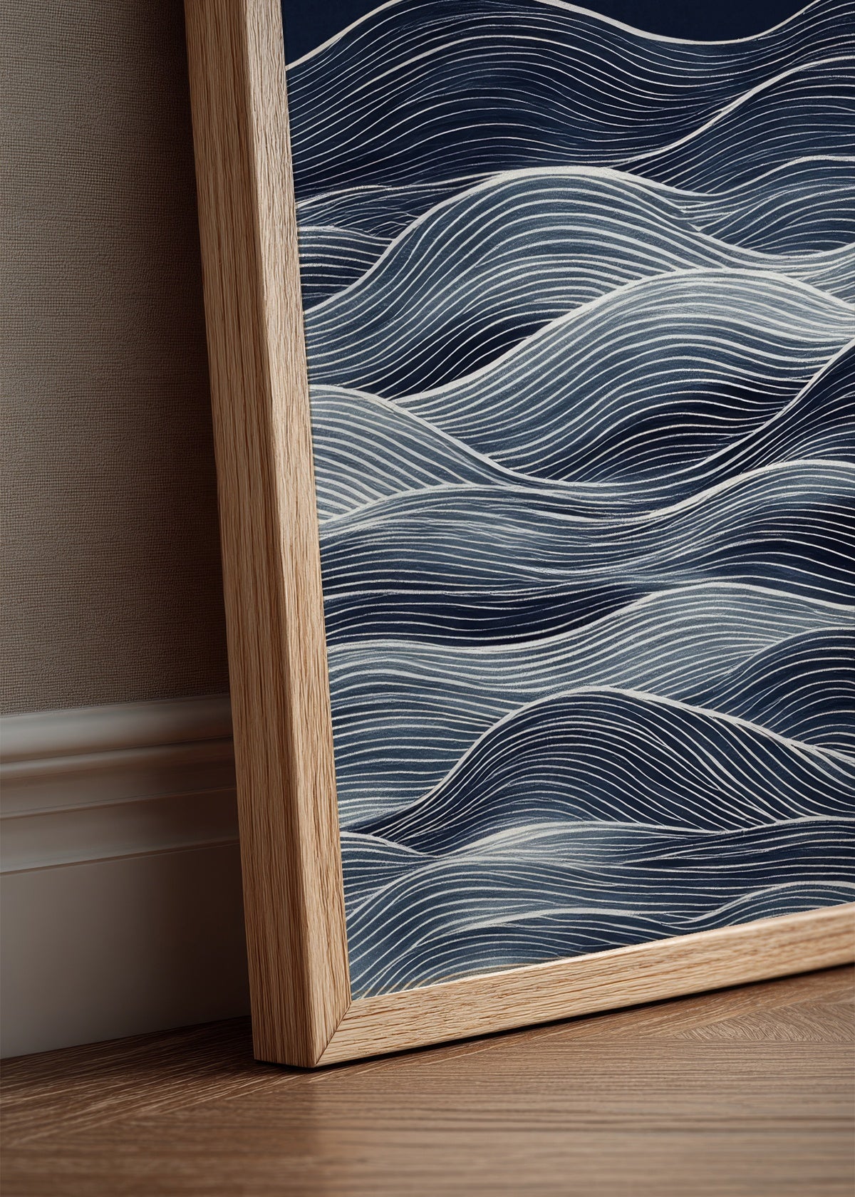 Minimalist blue and white abstract wave print in light oak frame, leaning against a beige wall in a modern, calm home interior.