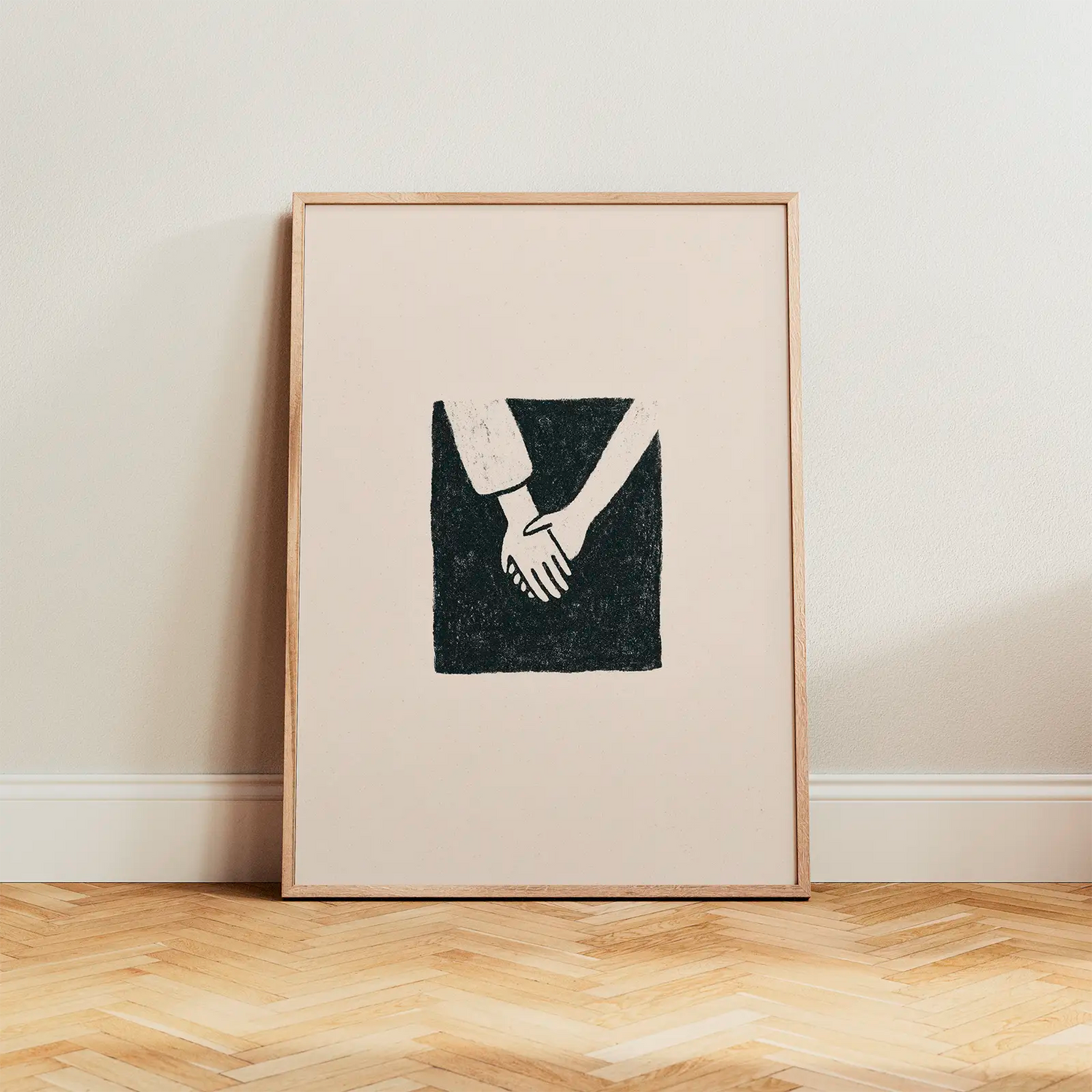 The 'Togetherness' poster with two hands holding, displayed in an oak frame leaning against a light wall on wooden flooring. Minimalist Scandinavian home decor with warm, soft light.