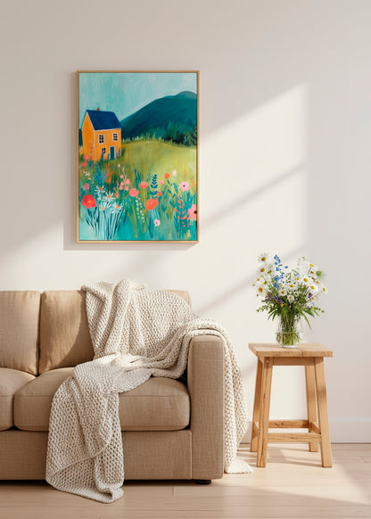 Canvas artwork of a yellow house in a colorful wildflower meadow hanging above a beige sofa in a bright living room.