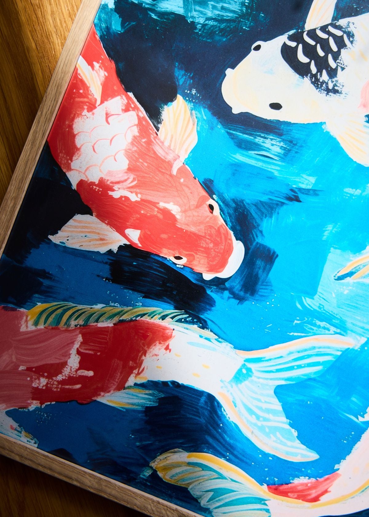 “Koi” poster close-up with bright orange and white fish, captured in natural sunlight next to a decorative ceramic koi.